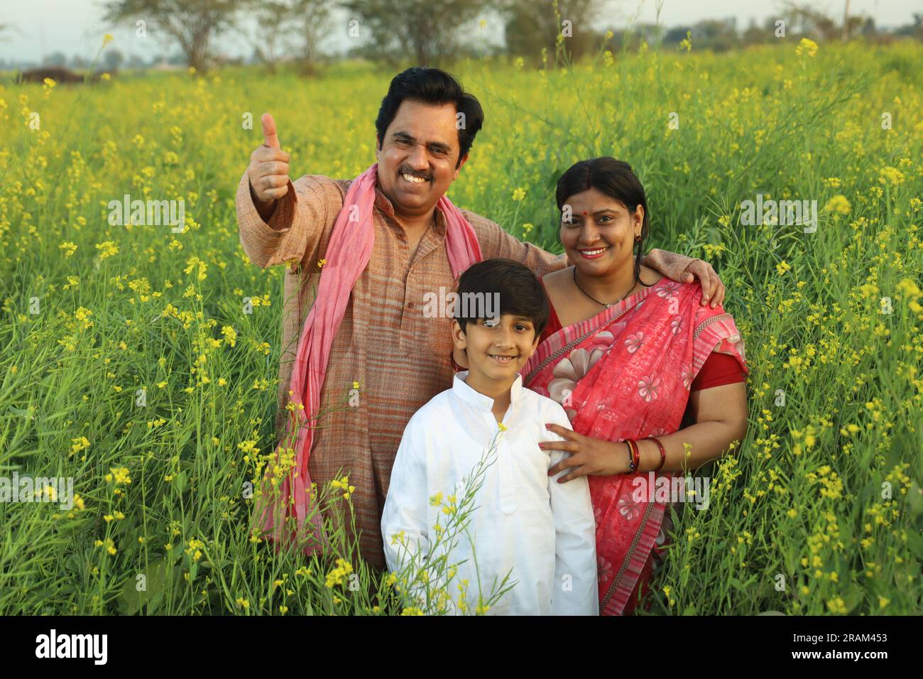 Happy Indian farmers family standing in mustard field in day time ...