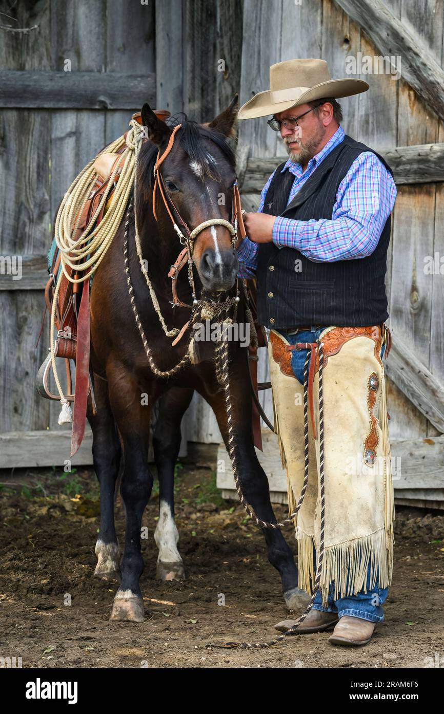Chance adjusting the tack on his horse; Dennis Ranch, Red Owl, South Dakota. Stock Photo