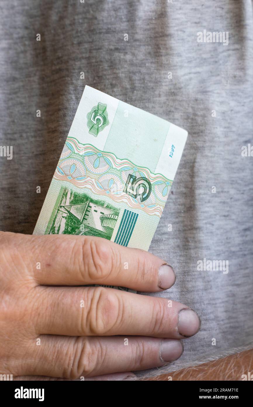 male working hands with dirty nails hold a banknote five rubles. Devaluation of human labor. Stock Photo