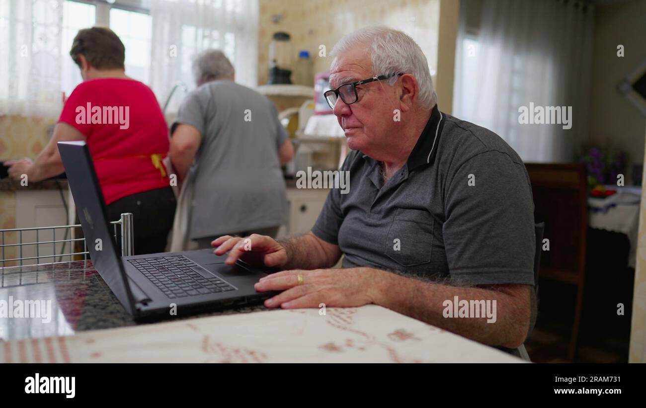Older man in front of laptop using modern technology in domestic ...