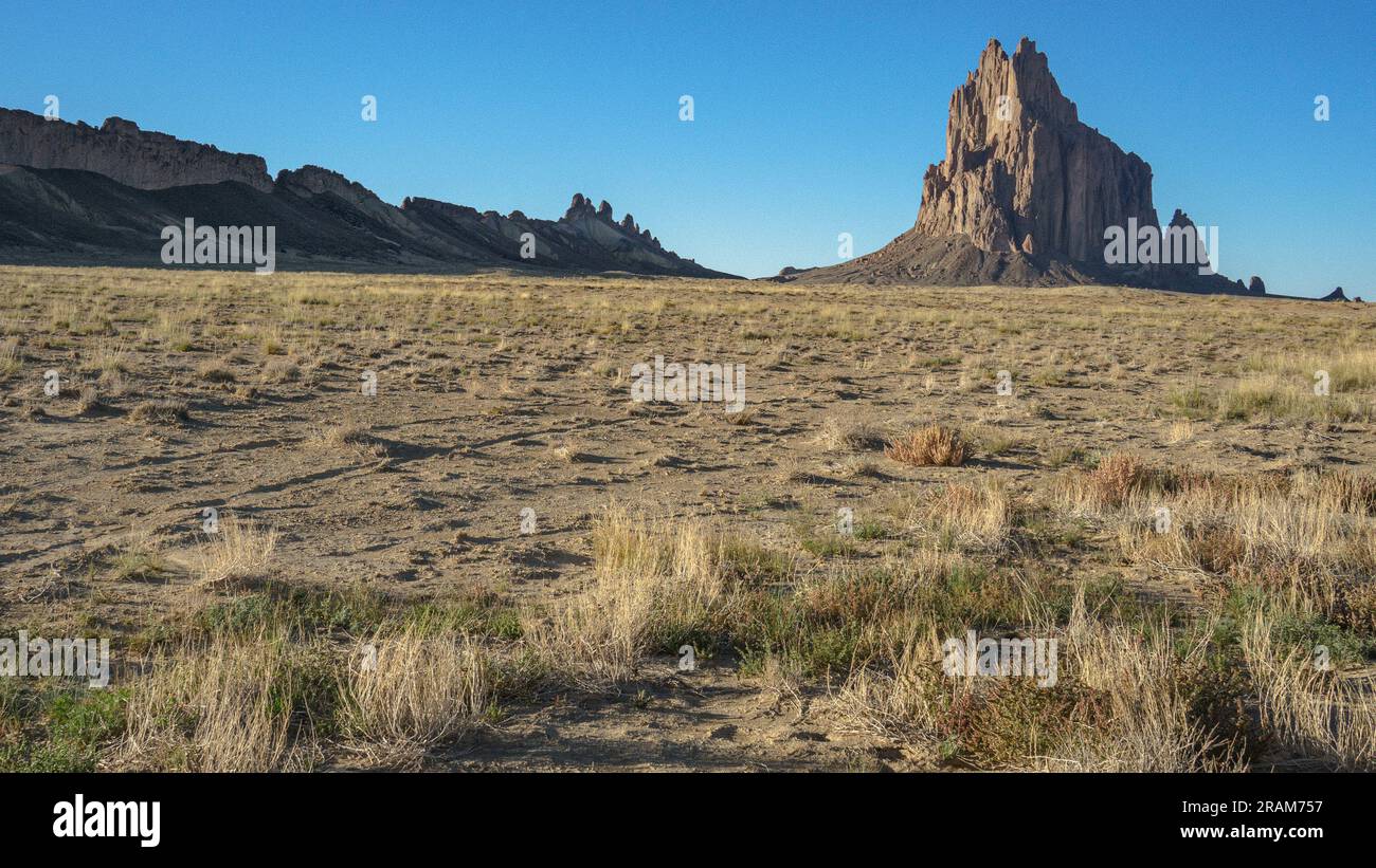 Shiprock (rock formation) sunlit in evening with clear, blue sky