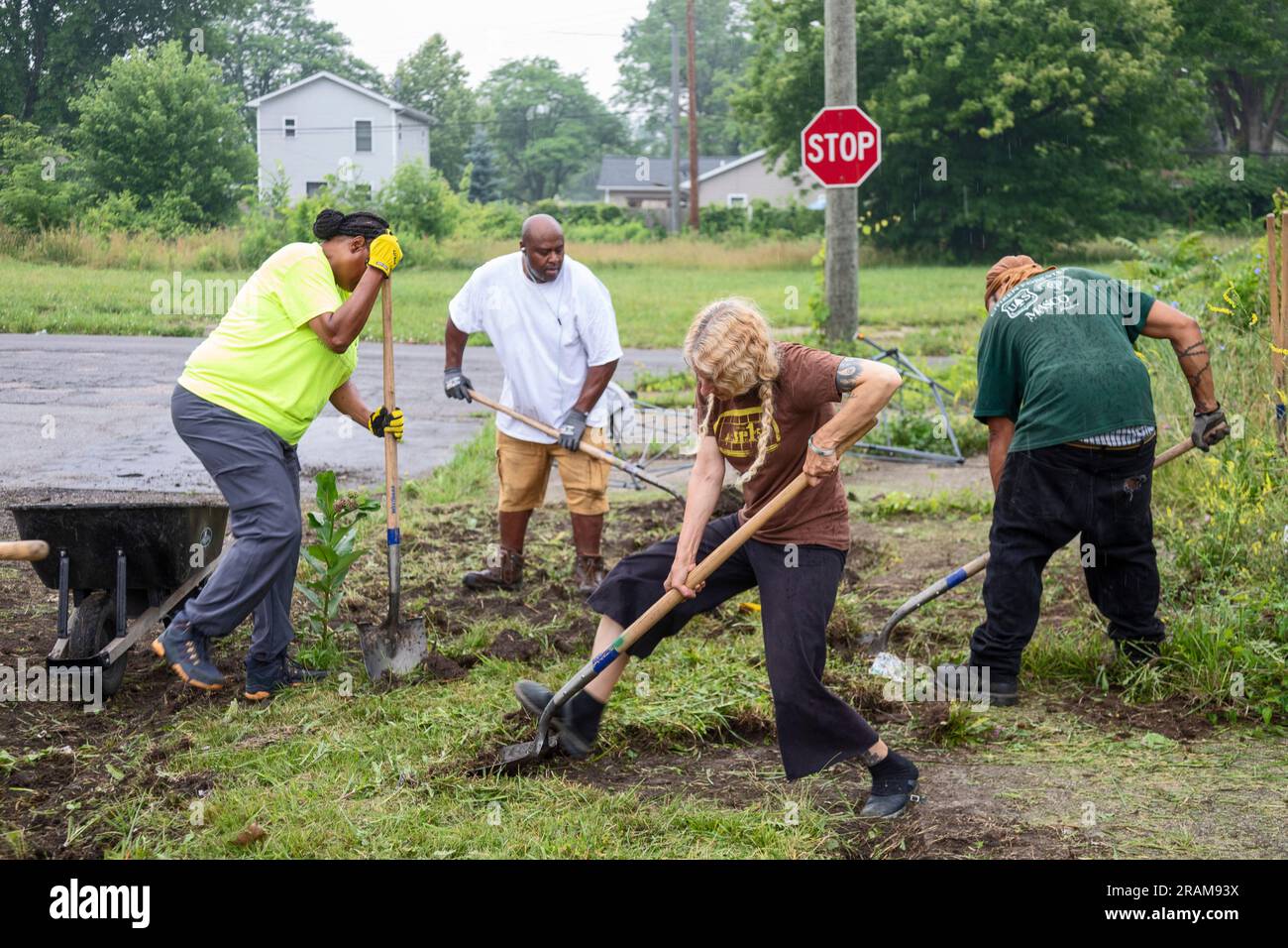Detroit, Michigan - Volunteers clear weeds and grass in preparation for planting a roadside garden in the Morningside neighborhood. Stock Photo