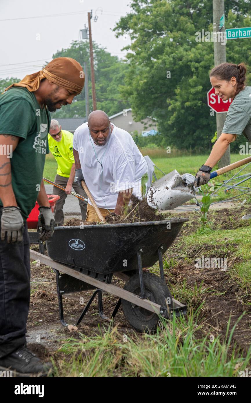 Detroit, Michigan - Volunteers clear weeds and grass in preparation for planting a roadside garden in the Morningside neighborhood. Stock Photo