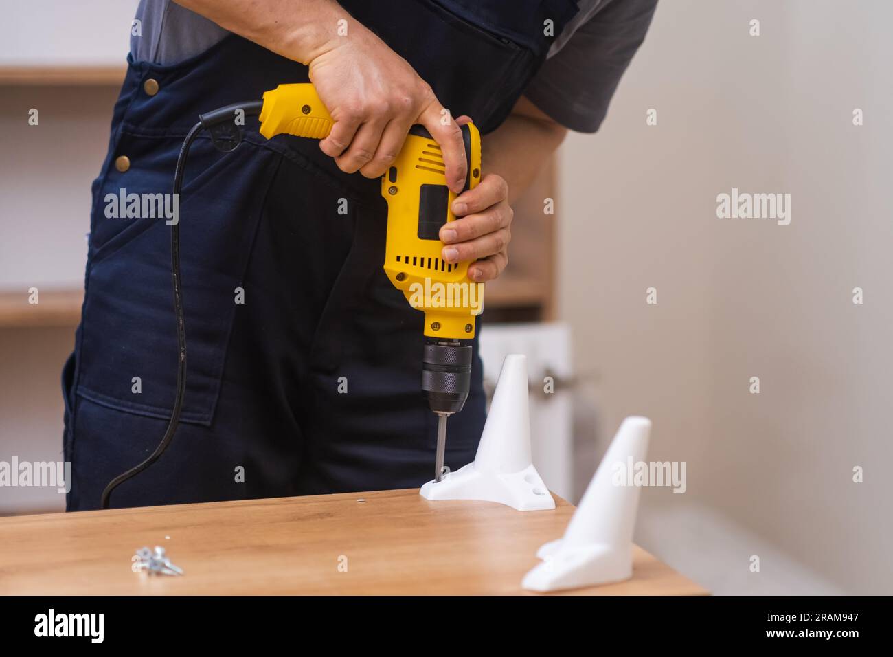 Professional furniture assembling and fixing employee attaching legs to with screwdriver