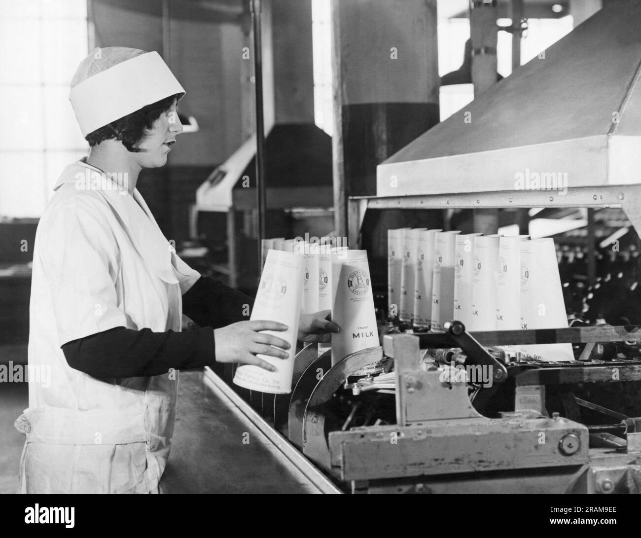 New York, New York:  c. 1928 Sheffield Dairy Farms workers using the new Sealcone paper containers in which to pack milk, replacing the glass bottle. They are lighter, they don't break, and pack twice as efficiently due to their conical shape. Here the containers are being coated with paraffine to keep them from leaking. Stock Photo