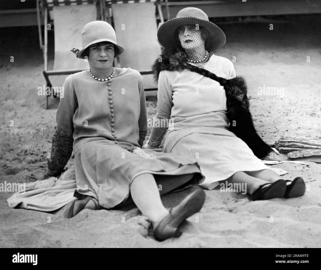 Palm Beach, Florida:   January 31, 1926. A New York society matron and her daughter  practice relaxing on a Florida beach. Mrs. Jerome Napolean Bonaparte and her daughter, Barbara Strebeigh Bonaparte eschew beach chairs for sitting in the sand. Stock Photo