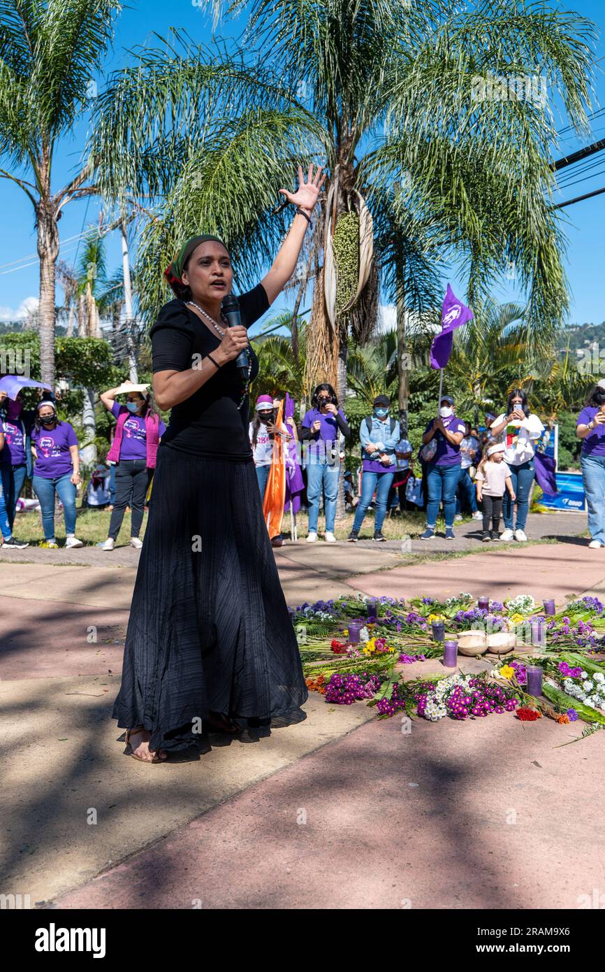 Tegucigalpa, Francisco Morazan, Honduras - December 11, 2022: Woman in Black Dress and Colorful Head Scarf Speaks in a Microphone by an Offering of Fo Stock Photo