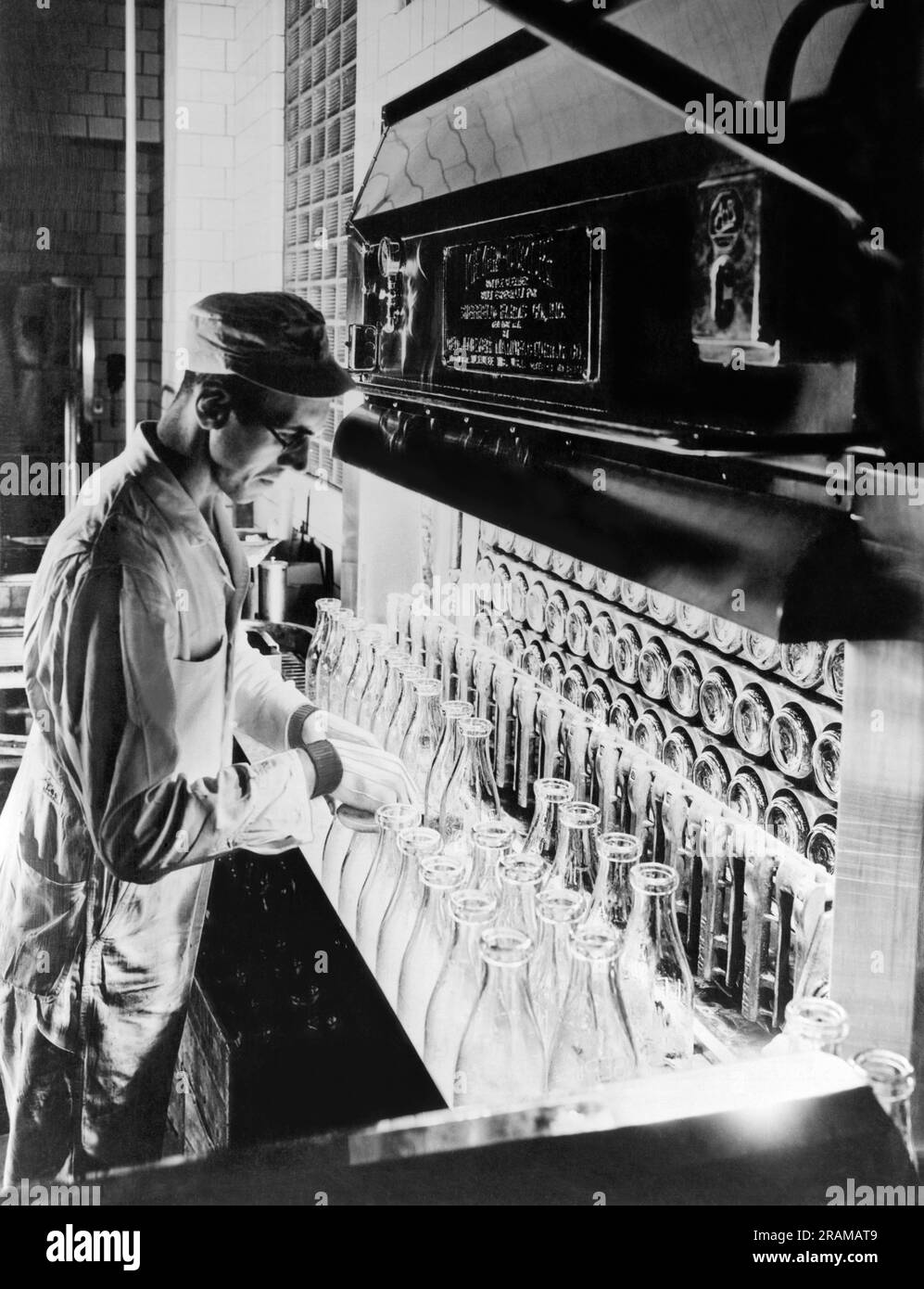 New York, New York:  c. 1926 A Sheffield Dairy Farms worker inspecting milk bottles during the sterilization process at their New York City plant. Stock Photo