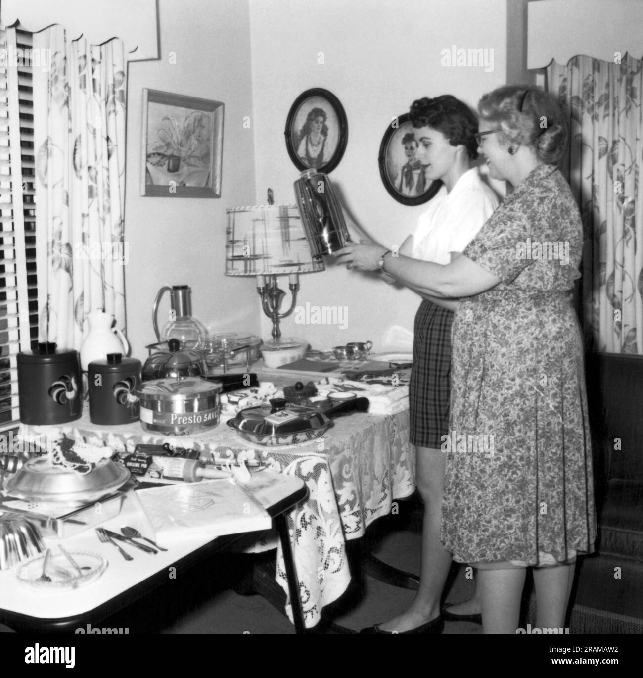 United States:  c. 1961 Two women at a housewares party look at a coffe pot. Stock Photo