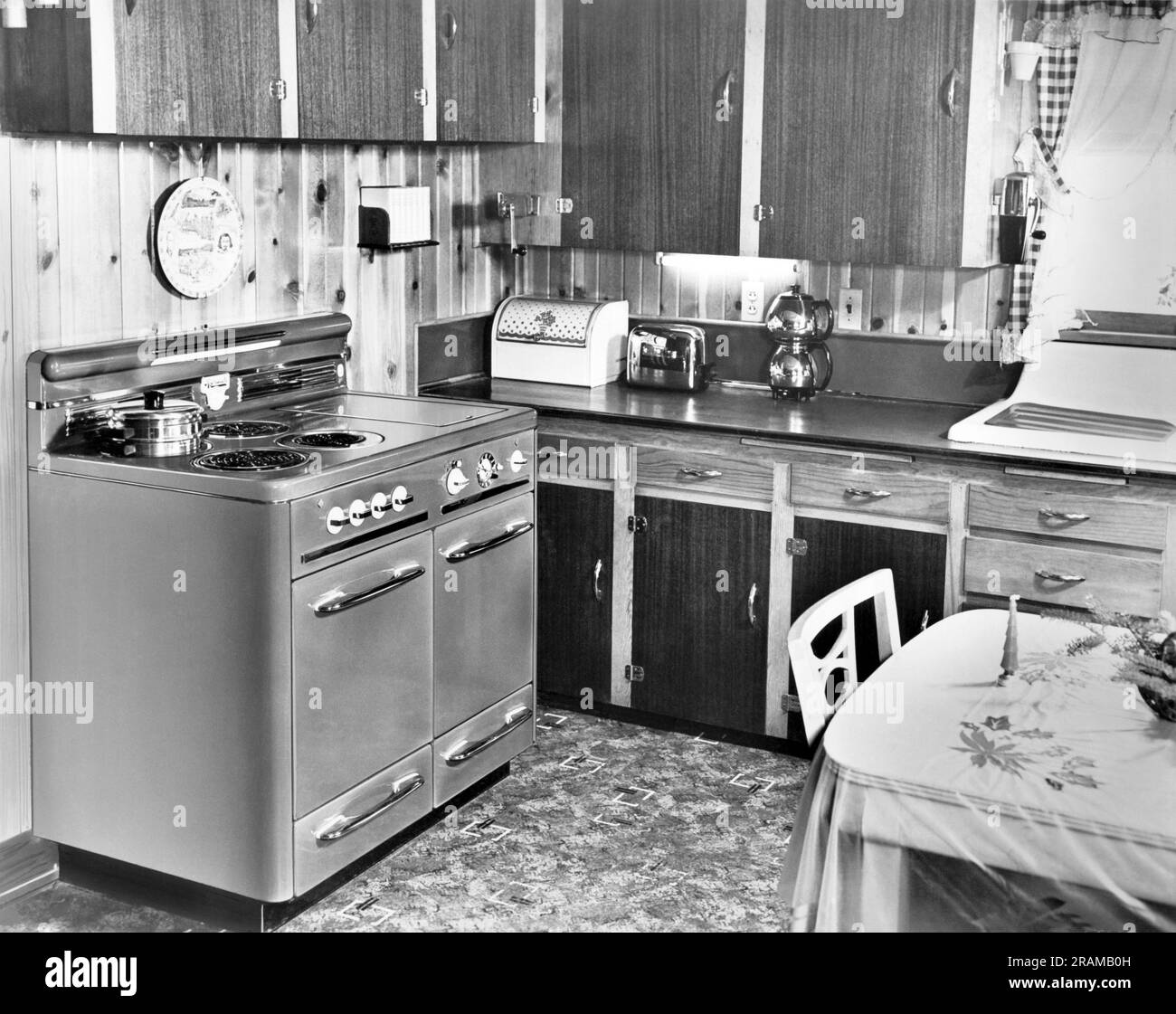 United States:  c. 1959 A wood paneled kitchen with a wall mounted can opener and coffee grinder and a Sunbeam Vacuum Drip Coffee Percolater. Stock Photo