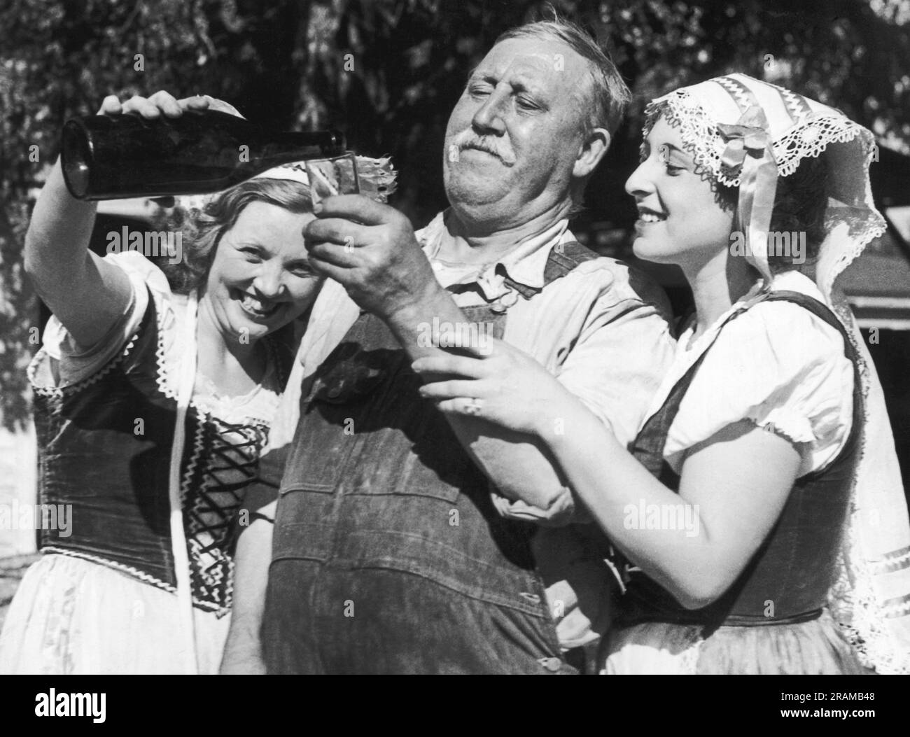 St. Helena, California:  August 24, 1934 Three cheerful members of the St. Helena Wine Festival pageant are celebrating their wine grape crop for the first time in thirteen years.  L-R are Jean Speare, Robert Camgros and Ethyl Byers. Stock Photo