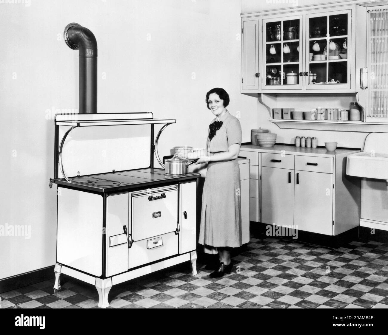 Beaver Dam, Wisconsin:  c. 1928. A woman stands in her kitchen cooking on her Monarch stove. Stock Photo