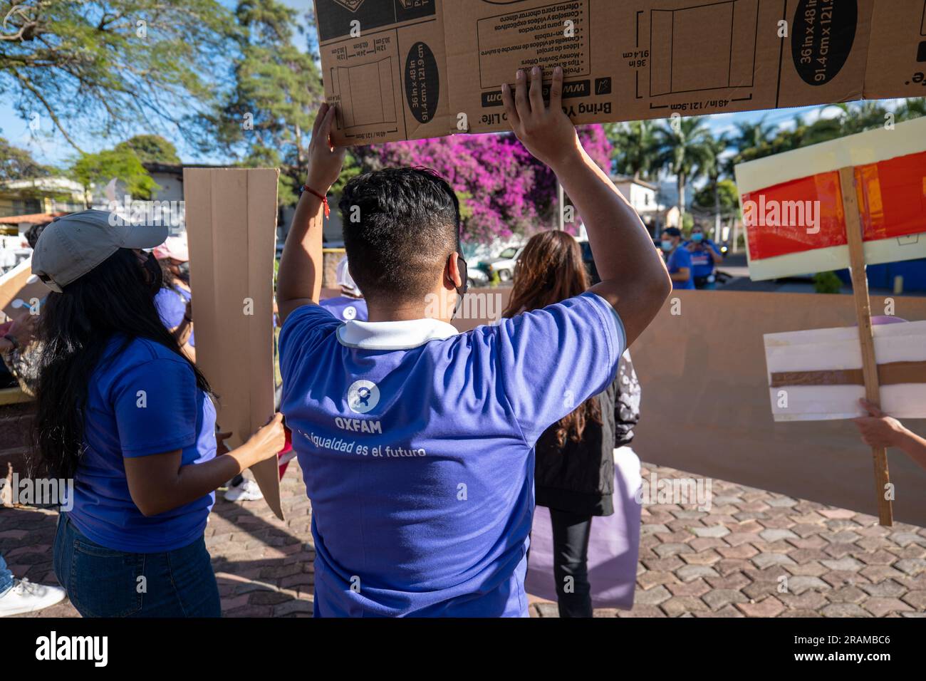 Tegucigalpa, Francisco Morazan, Honduras - December 11, 2022: Young Brown Adults Hold Cardboard Signs at Protest with Purple Shirts with Oxfam Logo Se Stock Photo