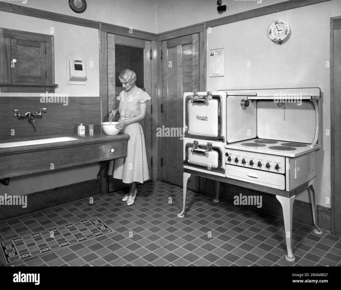 Beaver Dam, Wisconsin:  c. 1928. A woman cooking in her kitchen, which is equipped with a Monarch electric stove. Stock Photo