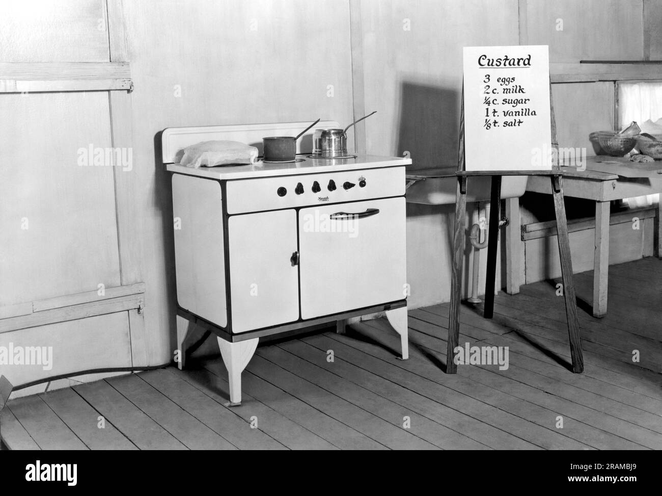 United States:  c. 1925. A stove in a kitchen with a recipe for custard mounted on an easel. Stock Photo