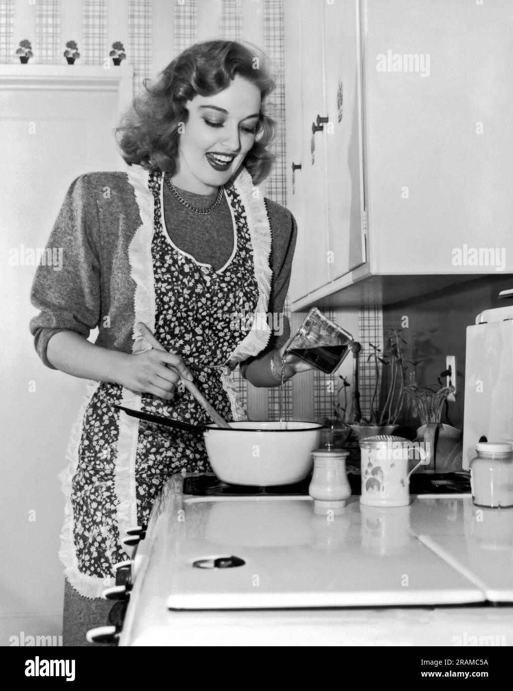 Hollywood, California:  1947. Actress Karin Booth preparing something delicious on the stove top. Stock Photo