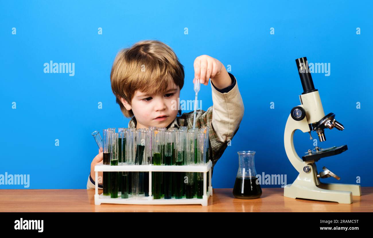 Child study biology chemistry. Educational experiment. Little boy working with test tubes and microscope in school classroom. School subject. Kid boy Stock Photo