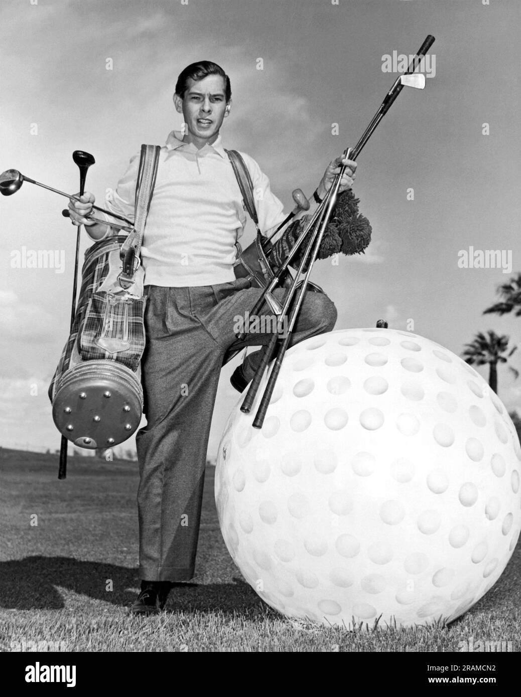 Las Vegas, Nevada:  c. 1958. A golfer holding two bags of clubs in search of one big enough for a three foot golf ball. Stock Photo