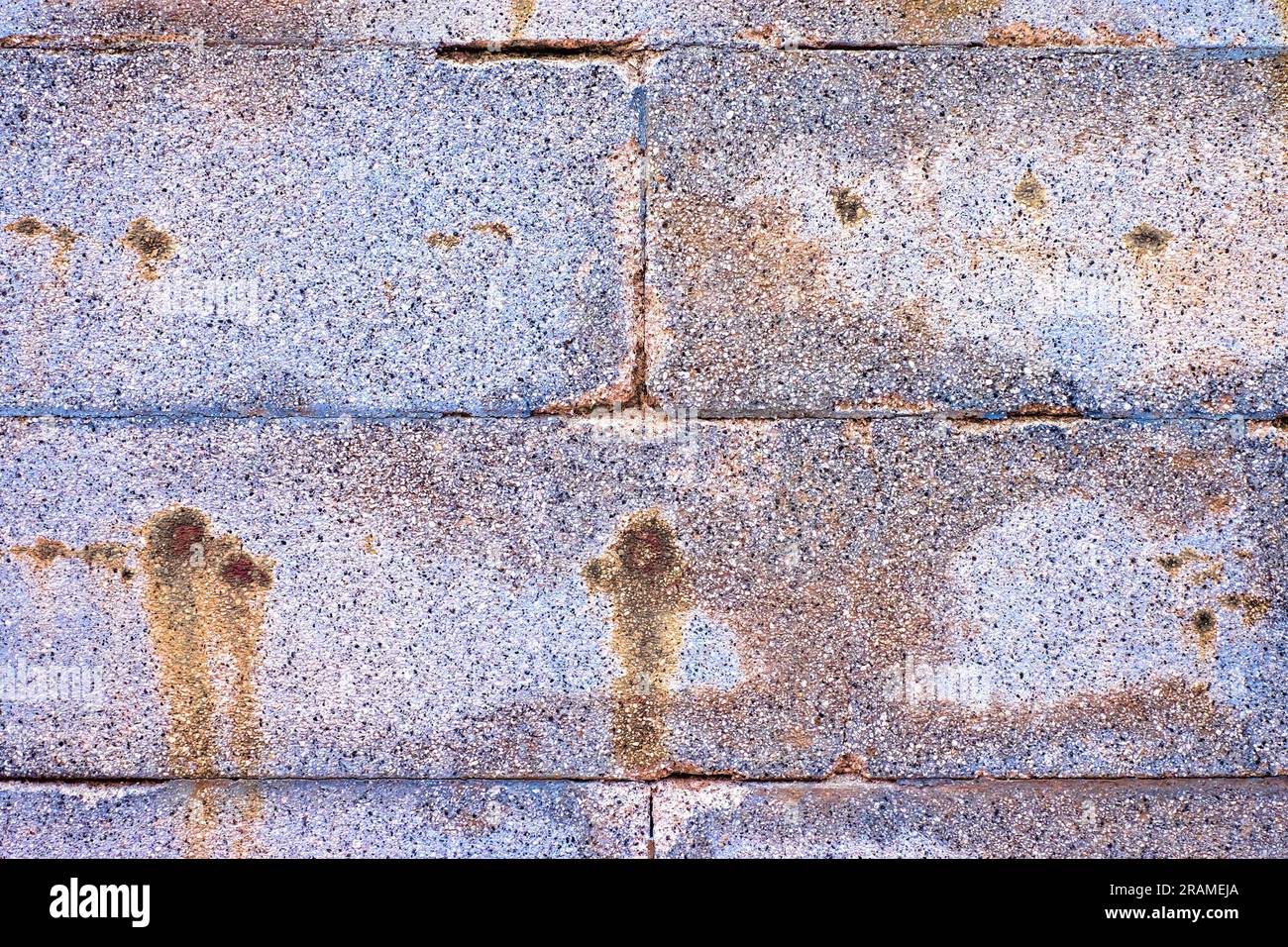 Aged colorful stone blocks, silver gray wall with rusty stains. Stock Photo