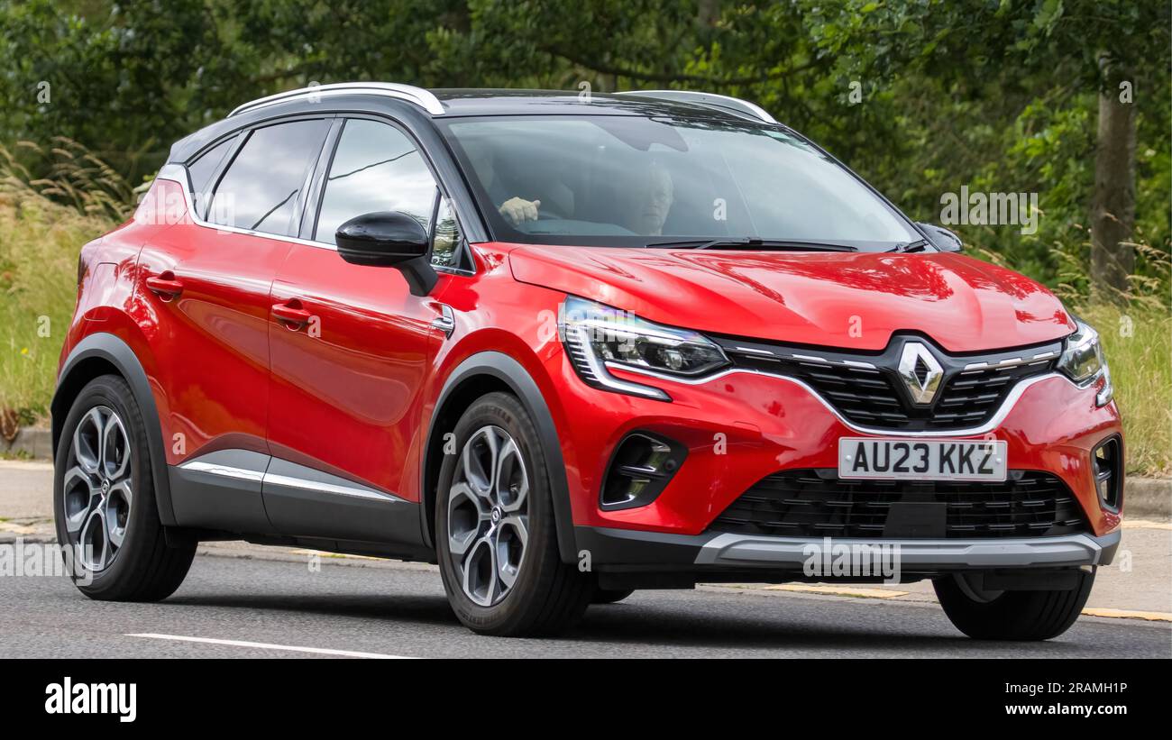 Milton Keynes,UK - July 2nd 2023. 2023 red hybrid electric RENAULT CAPTUR TECHNO E-TECH HEV AUTO  car travelling on an English country road Stock Photo