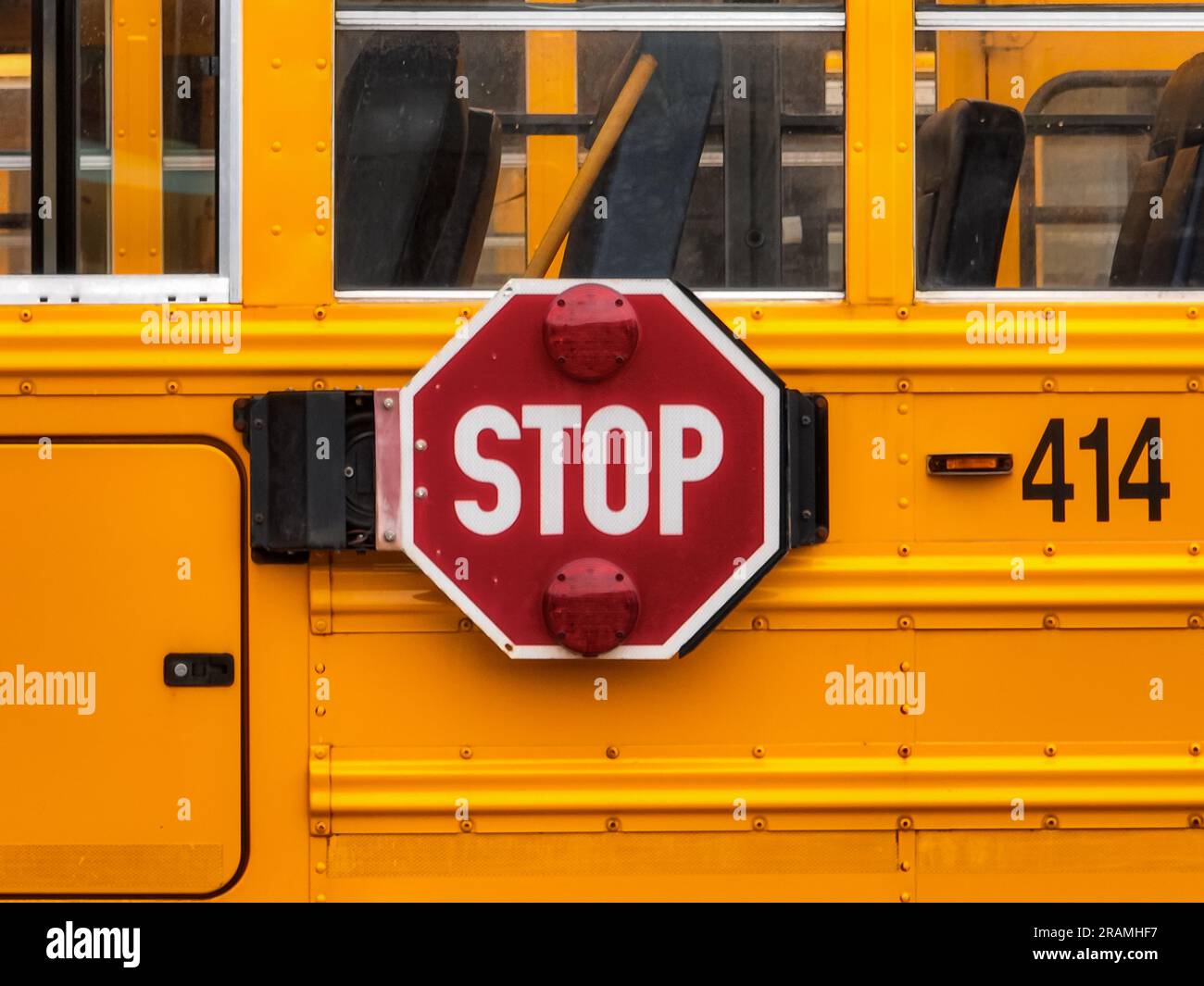 View of the drivers side of a yellow school bus in a parking lot. Stock Photo