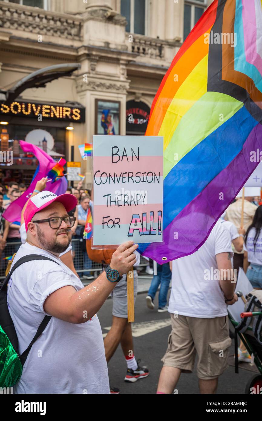 Bear holding a placard demanding a ban on conversion therapy for all, with progress flag during the Pride in London parade Stock Photo