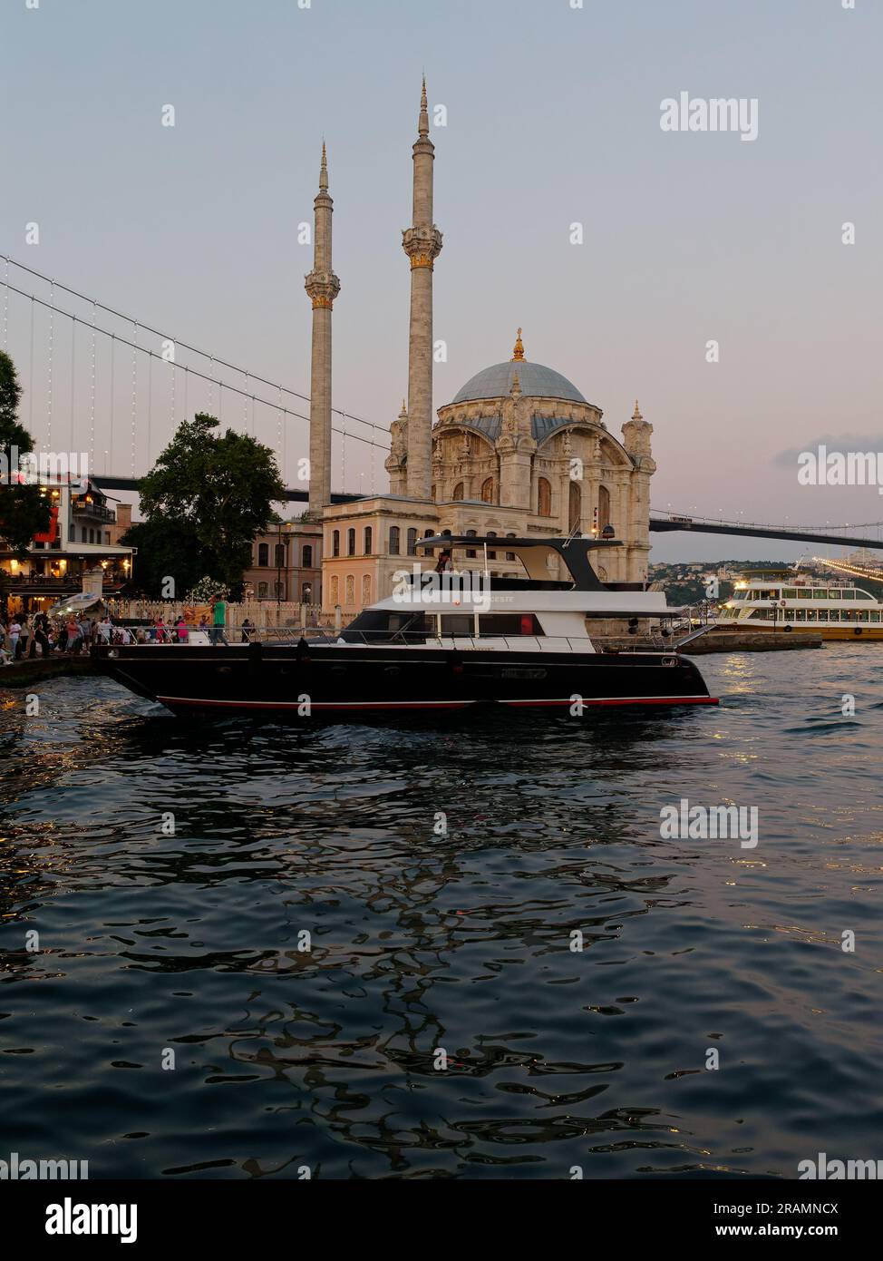 Luxury Yacht  on the Bosporus waterfront beside the Mosque in the  Ortaköy neighbourhood, Beşiktaş district, Istanbul, Turkey Stock Photo