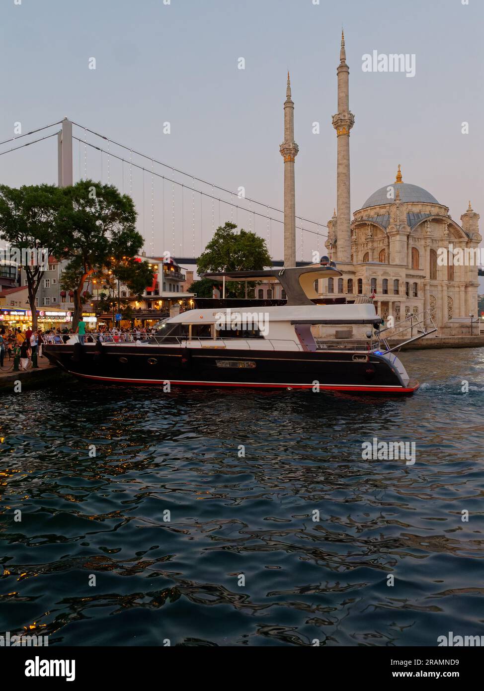 Luxury Yacht  on the Bosporus waterfront beside the Mosque in the  Ortaköy neighbourhood, Beşiktaş district, Istanbul, Turkey Stock Photo