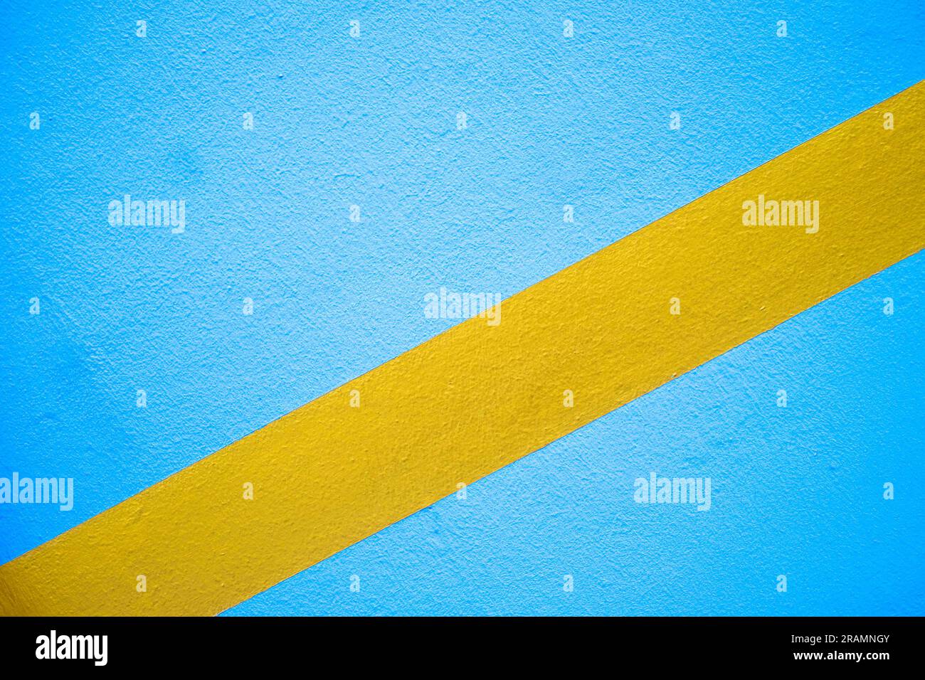 Diagonal broad golden yellow stripe on a blue empty surface Stock Photo