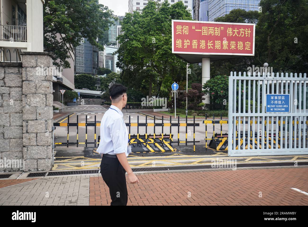 A man walks past the entrance gate to the Chinese People's Liberation Army Forces Hong Kong Building in Hong Kong. The Central Barracks Amethyst Block is one of the barracks of Chinese People's Liberation Army basement, it is located next to the Central Government Offices. Stock Photo