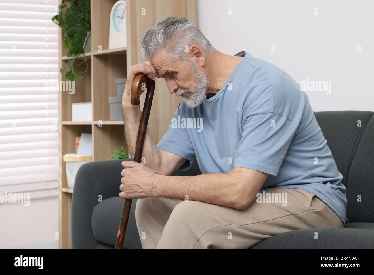 Senior man with walking cane sitting on sofa at home Stock Photo - Alamy