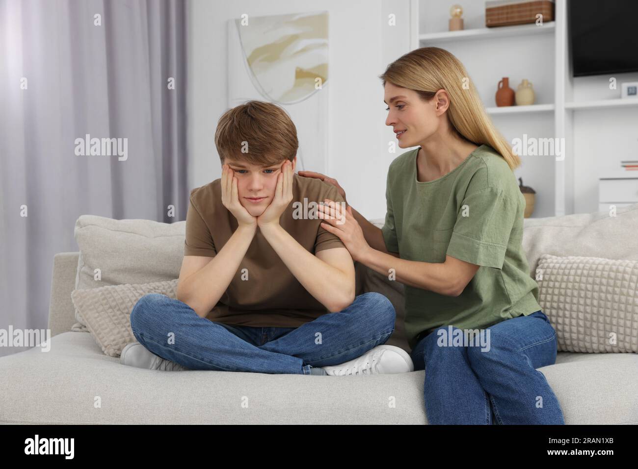 Mother comforting her upset teenage son at home Stock Photo