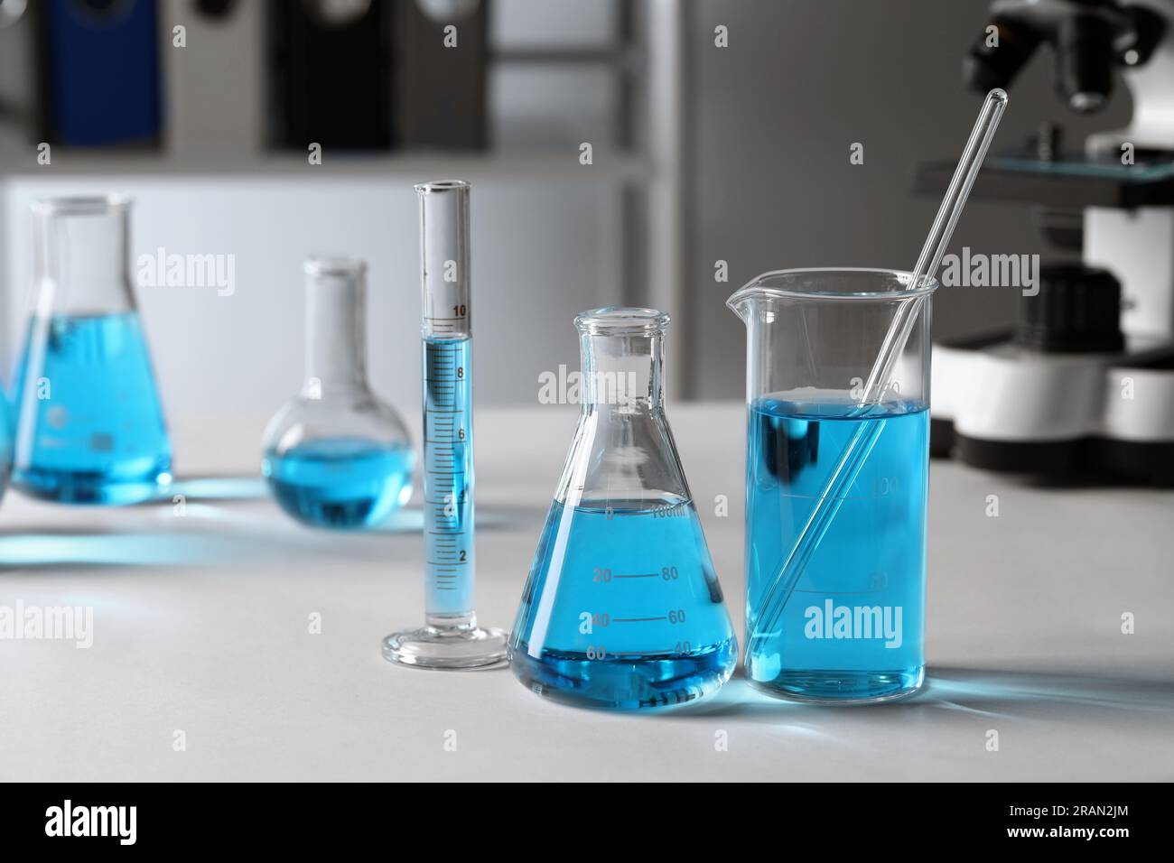 Different laboratory glassware with light blue liquid on table Stock ...