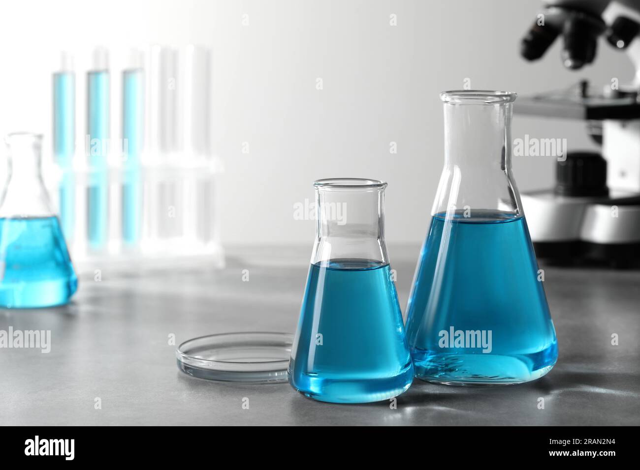 Different laboratory glassware with light blue liquid on table. Space ...