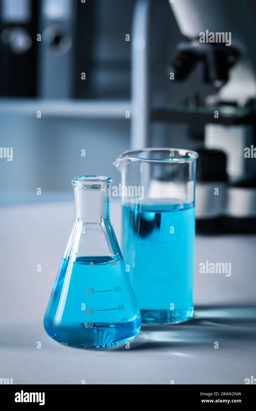 Different laboratory glassware with light blue liquid on table Stock ...