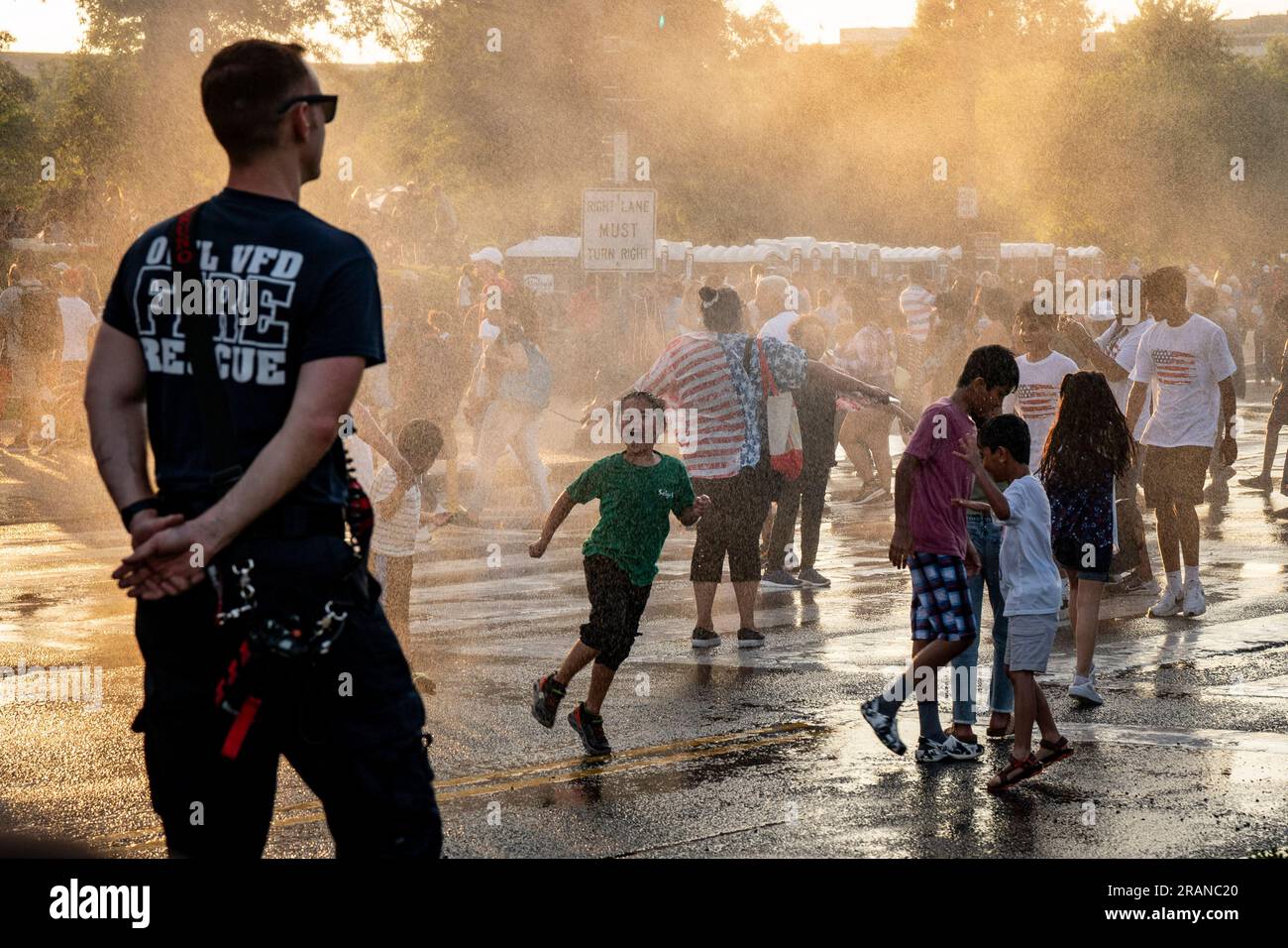 Washington, United States. 04th July, 2023. Volunteer Firefighter Frank Bruno watches as children enjoy the spray of water from a Mobile Ventilation Unit as crowds gather prior to the annual 4th of July fireworks display on the National Mall in Washington DC on Tuesday, July 4, 2023. Photo by Ken Cedeno/UPI. Credit: UPI/Alamy Live News Stock Photo