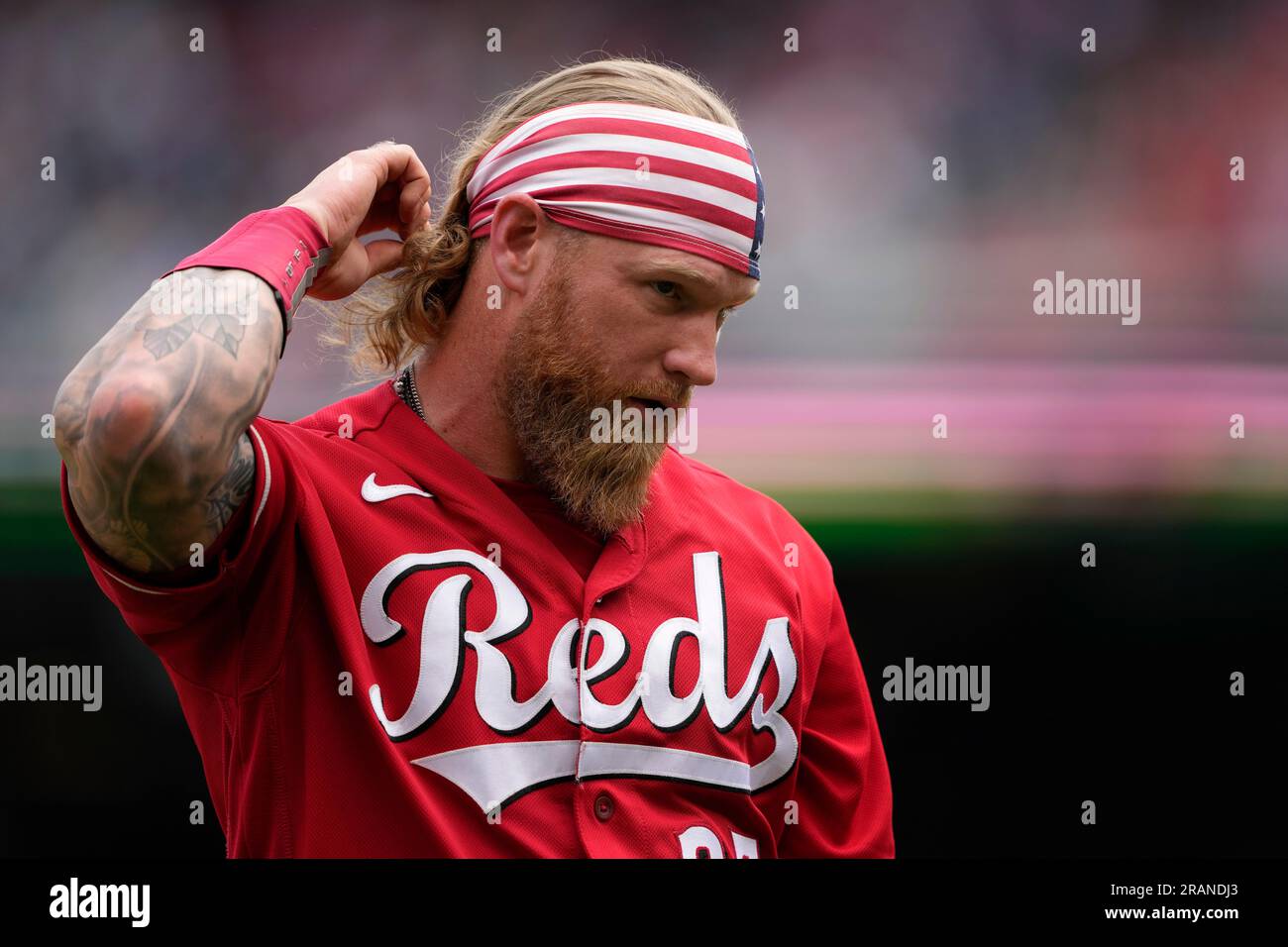 Cincinnati Reds' Jake Fraley adjusts a headband depicting the American flag  as he walks on the field between innings of a baseball game against the Washington  Nationals, Tuesday, July 4, 2023, in