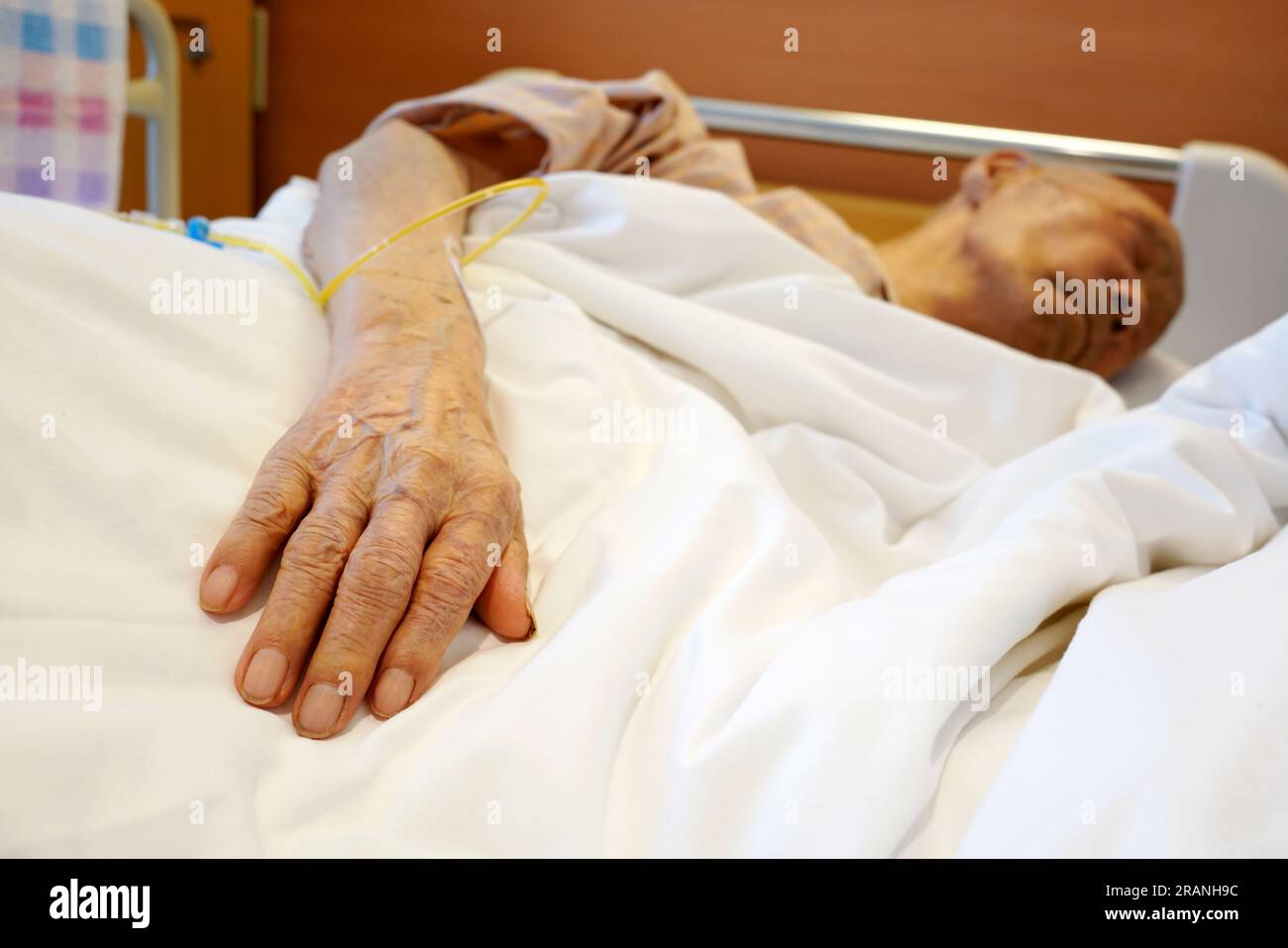 Elderly patient hand with intravenous drip at the hospital bed Stock Photo