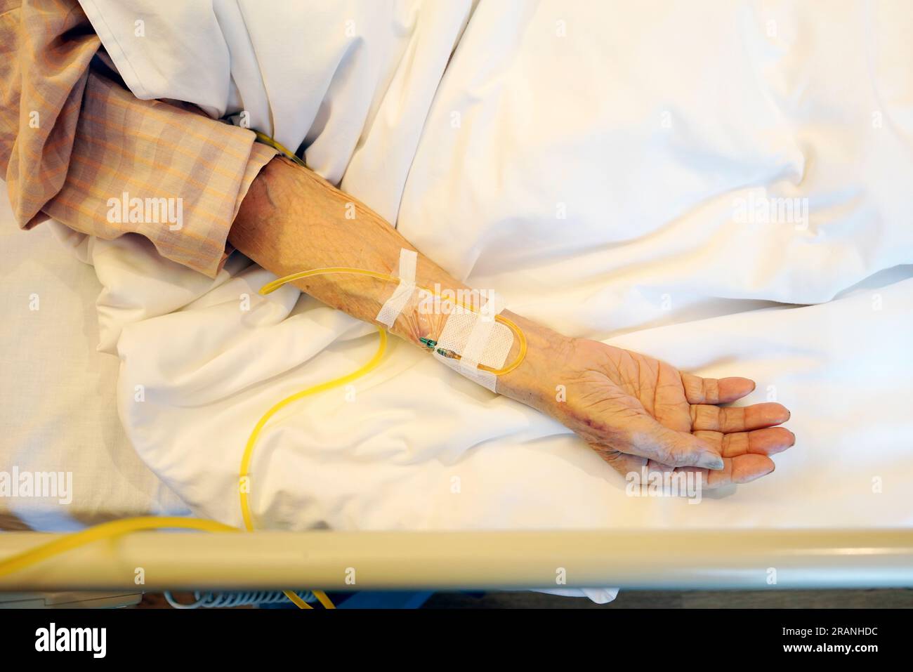 Closeup of elderly patient hand with intravenous drip at the hospital bed Stock Photo