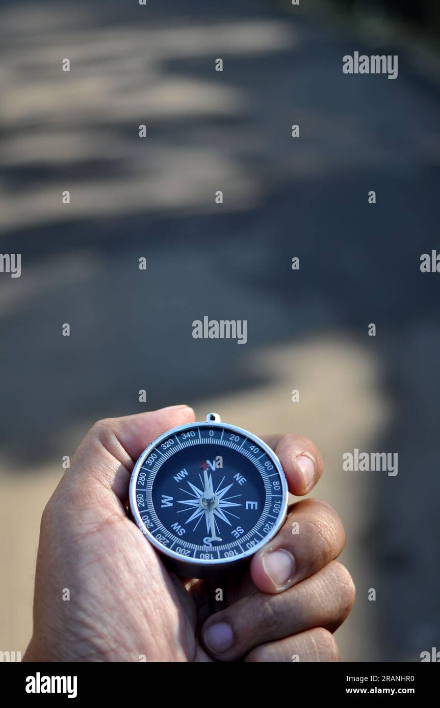 Close-up holding navigation compass outdoor blur background Stock Photo