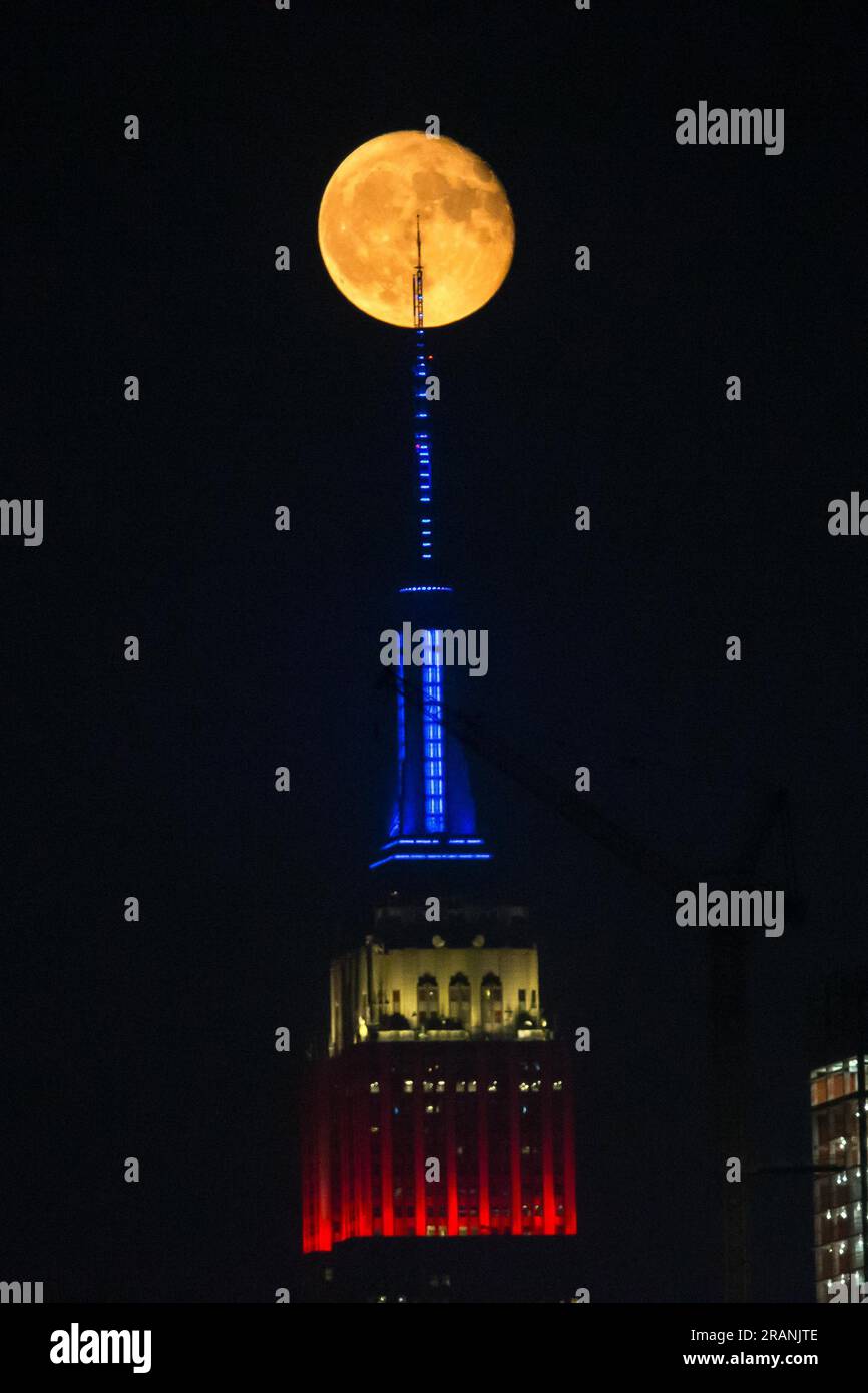 New York City, United States. 04/07/2023, Full moon rises behind Empire ...