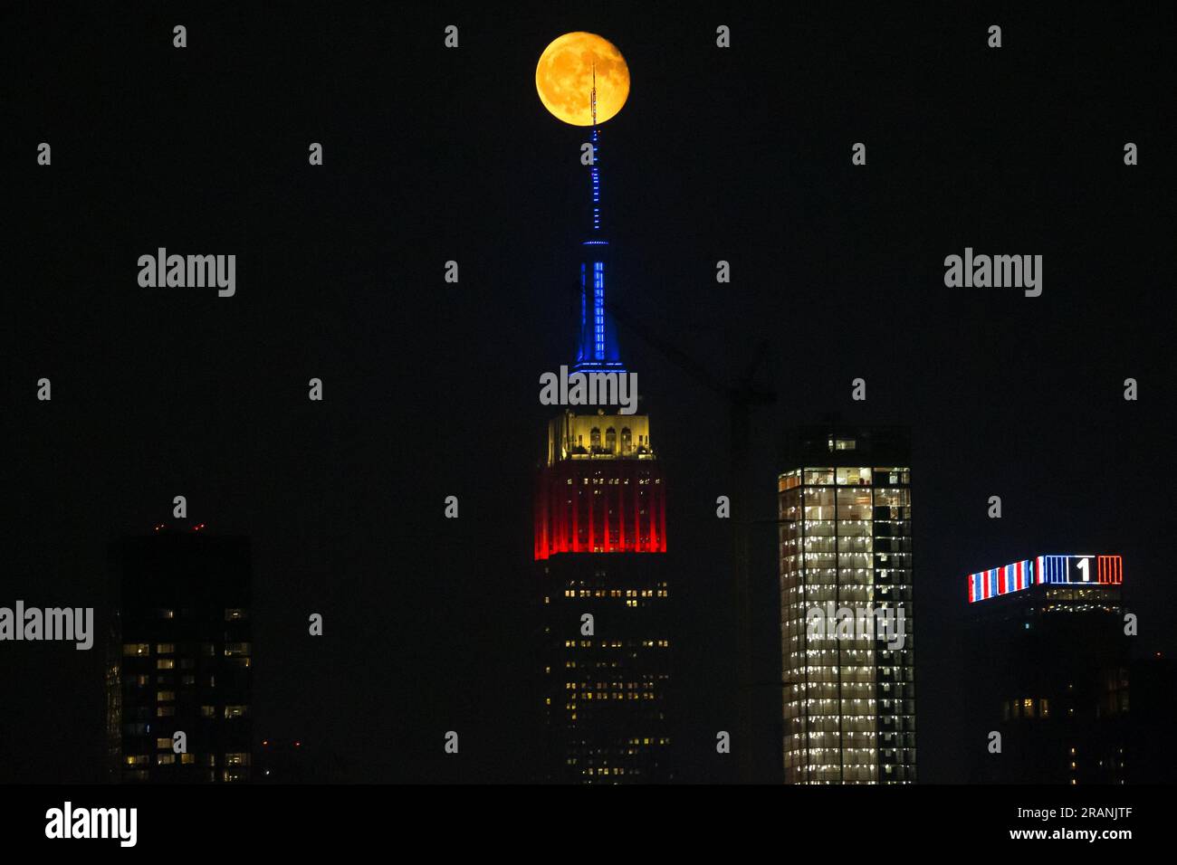 New York City, United States. 04/07/2023, Full moon rises behind Empire ...