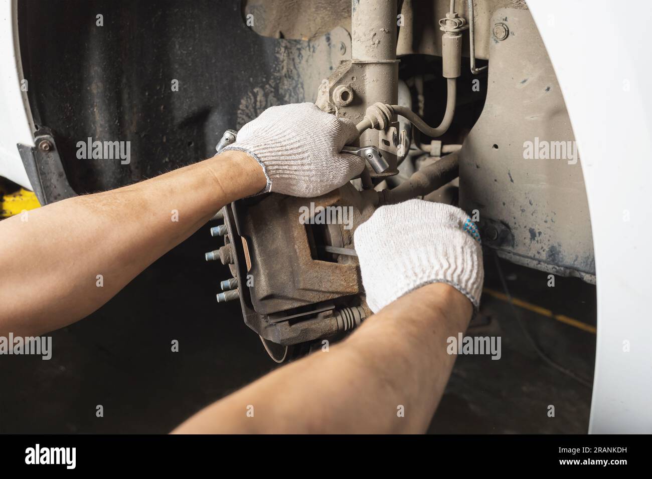 An auto mechanic is engaged in the maintenance of the brake system of a passenger car, removes a faulty front caliper to replace it Stock Photo