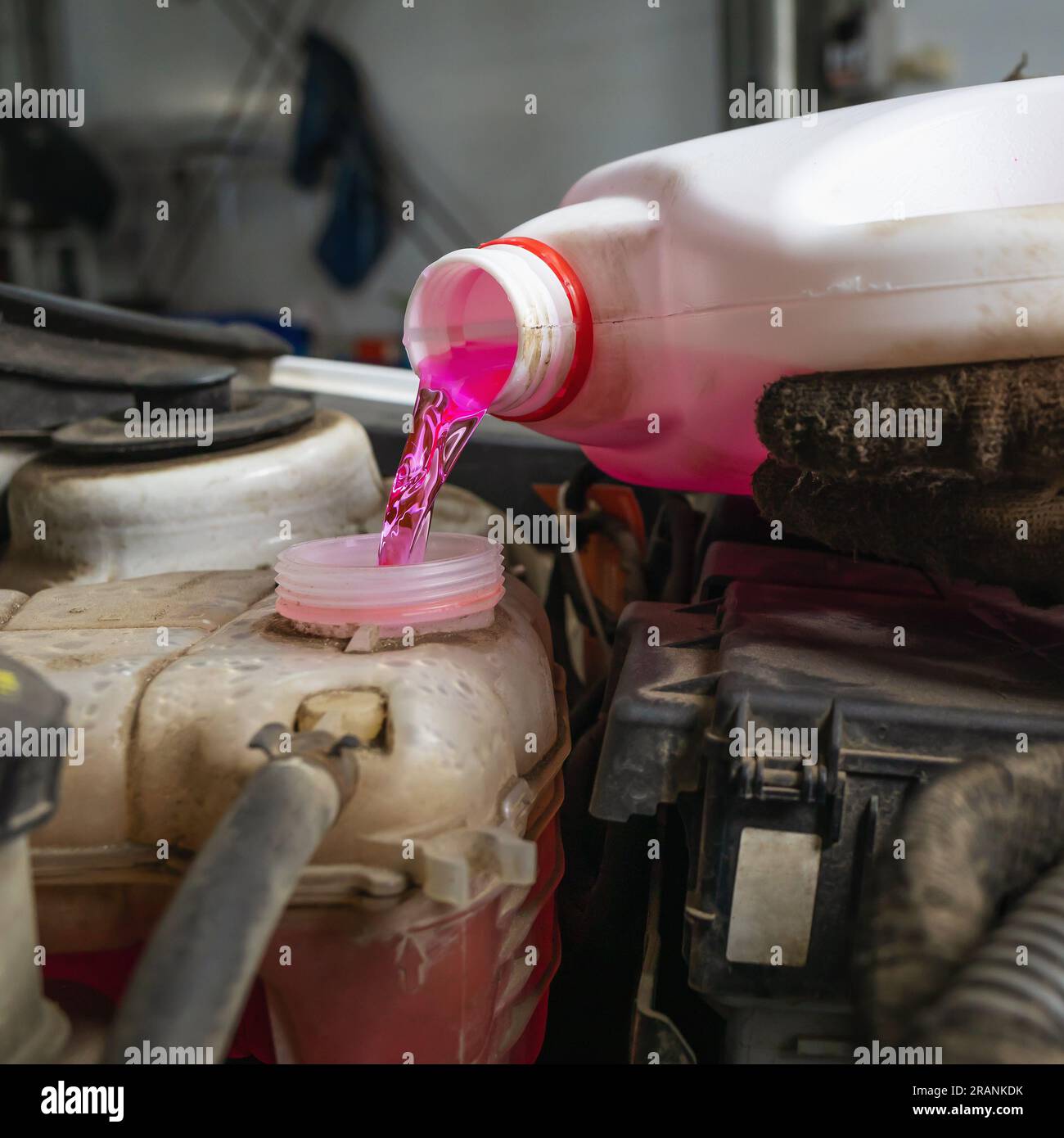 The process of pouring antifreeze into the expansion tank of a car, a