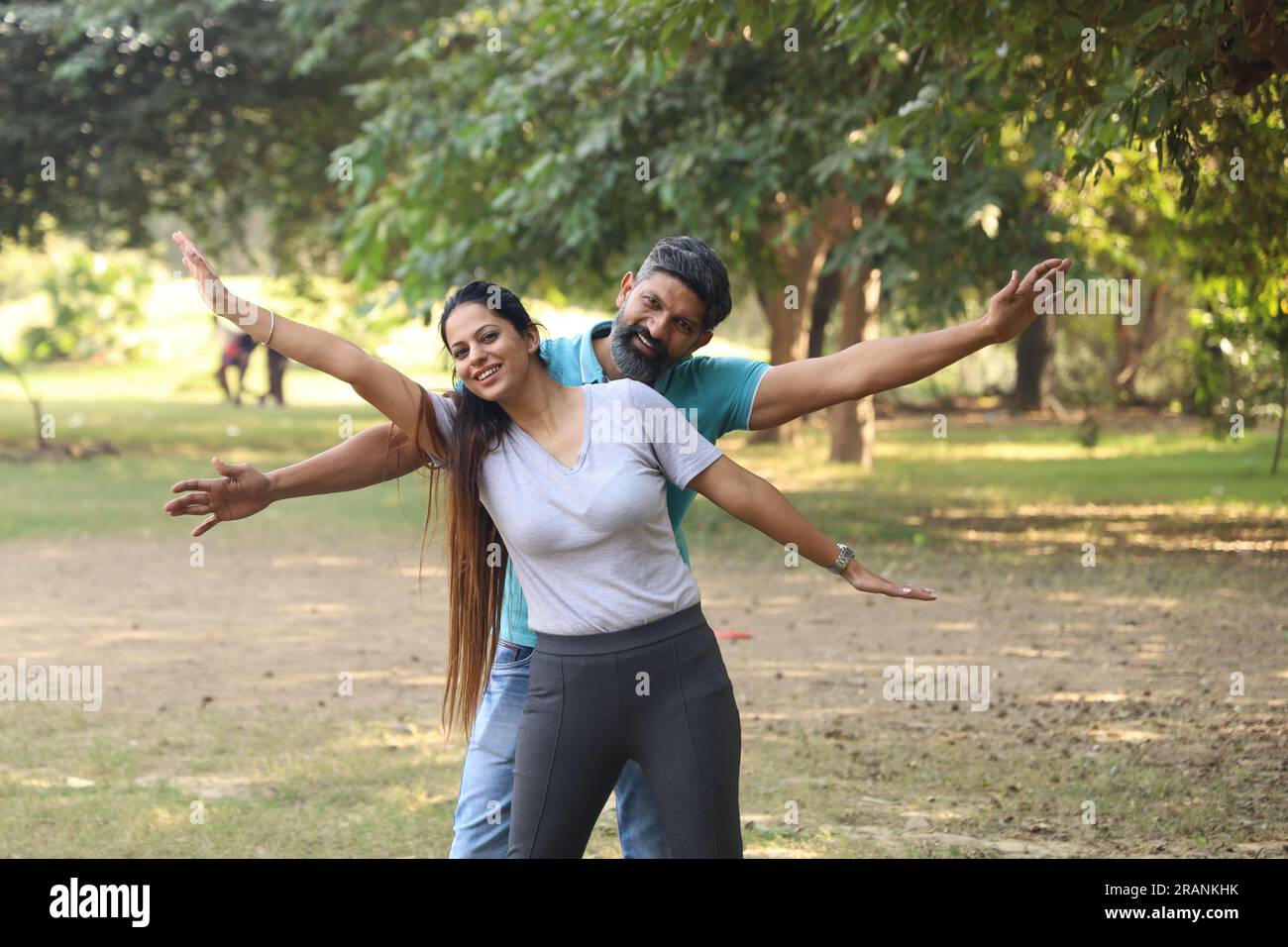 Portrait of a happy Indian couple sitting on the pedestal in the park ...