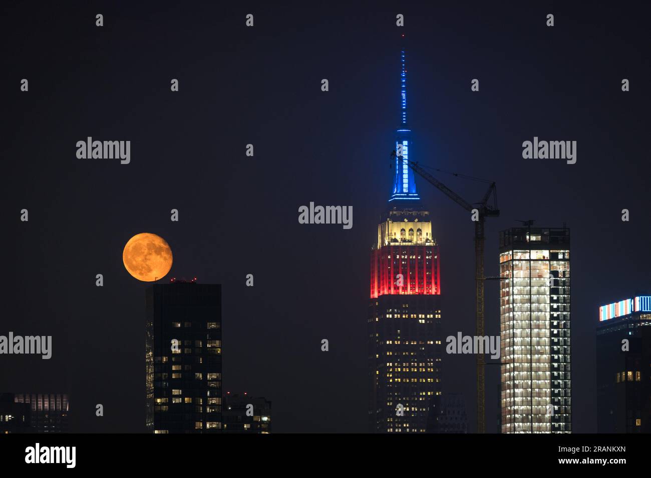 New York City, United States. 04/07/2023, Full moon rises behind Empire ...