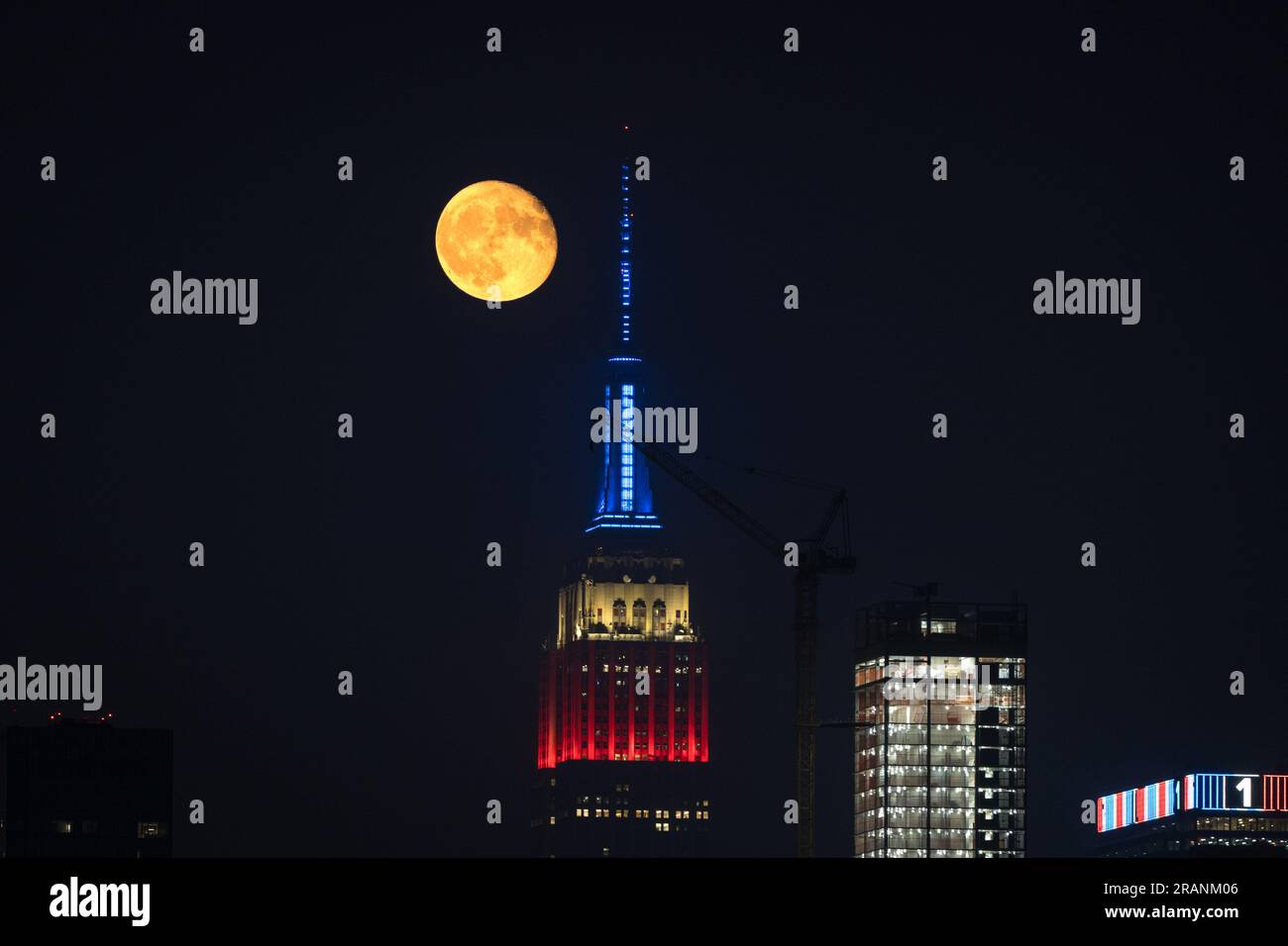New York City, United States. 04/07/2023, Full moon rises behind Empire ...