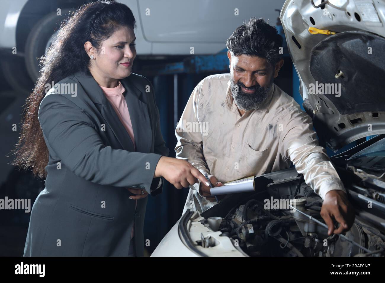 Mechanic standing with happy customer shaking hands. The customer is satisfied to get delivery on time. Complete car report in hand. Stock Photo