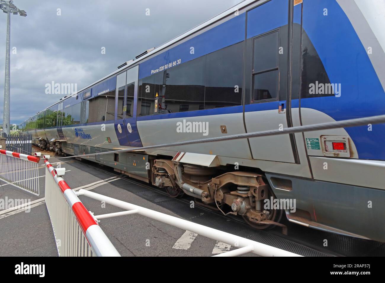 NI Railways train passes level crossing safely at Bushmills Rd, Coleraine, Northern Ireland, UK,  BT52 2BN Stock Photo