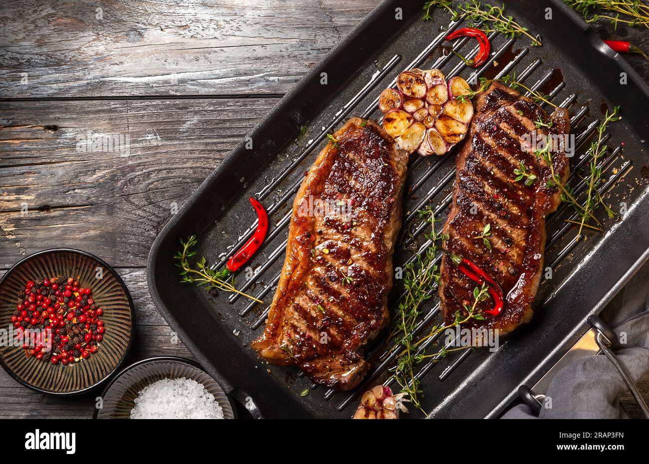 Grilled striploin steak with spices and herbs on grill iron pan.The strip  steak, also called a New York strip Stock Photo - Alamy